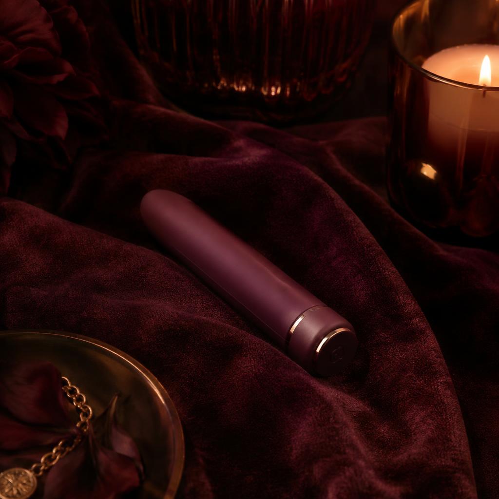 Slim burgundy bullet vibrator on dark velvet