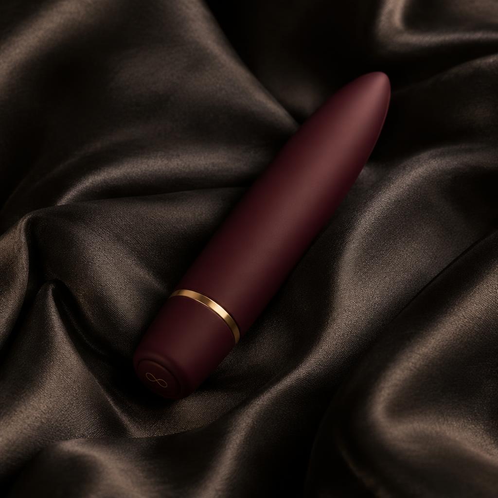 Slim burgundy bullet wellness device on dark silk